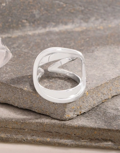 Nahaufnahme eines unregelmäßigen Silberrings auf Stein für modernes Design