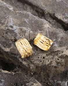 Macro shot of S925 hallmark on irregular gold coiled earrings with zircon stones