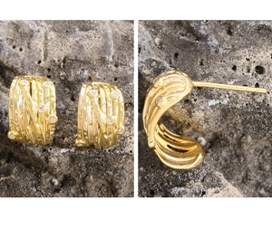 Detail of gold coiled zircon stud earrings with S925 silver stamp on dark stone