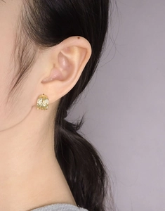 Detail of gold textured hoop earring with small zircons worn by a model