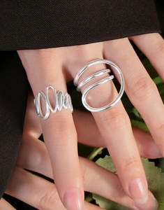 Detailed view of layered wavy and geometric silver rings on hand with professional polish