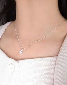 Detail of S925 sterling silver star pendant necklace on model with white knit cardigan