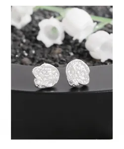 Detailed view of silver rose-shaped stud earrings with lava texture and small stones