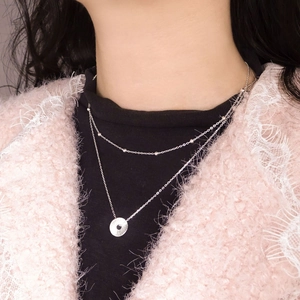 Double-layered S925 sterling silver necklace with textured round coin pendant on a model