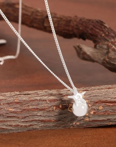Detailed close-up of a silver star and bead pendant necklace on a natural twig background