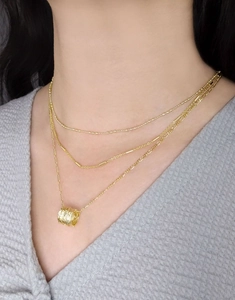Primo piano della collana a tre strati in oro S925 con pendente a trama ondulata a spirale
