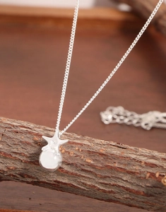 Macro view of S925 silver star necklace with a white pearl on a wooden texture base