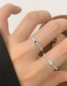 Detailed view of layered S925 sterling silver rings with zircon stones on a model hand