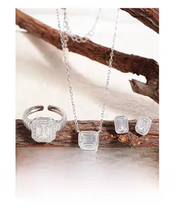 Macro shot of silver jewelry set with emerald cut zircons on natural wood branch