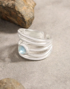 Macro detail of multi-layer silver aquamarine ring on natural textured stone background