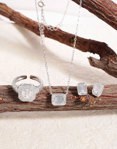 Macro shot of silver jewelry set with emerald-cut zircon stones on a wooden branch