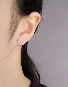 Detail shot of silver S925 earrings with irregular lava texture worn by a model