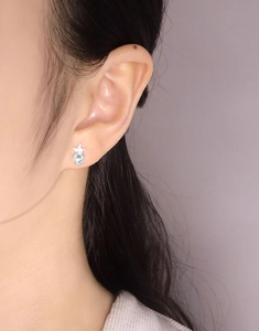 Gros plan d'une boucle d'oreille étoile en argent S925 avec cristal sur l'oreille du mannequin