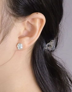 Close-up of irregular lava texture silver stud earrings worn on a female ear