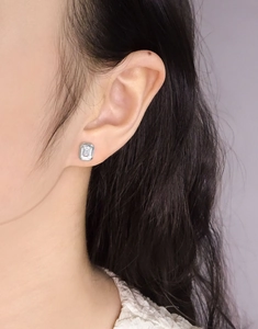 Detail view of emerald cut zircon stud earring in S925 silver on a woman's ear