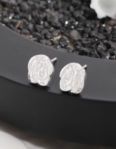 Macro detail of silver S925 earrings with lava floral texture and tiny zircon inlay