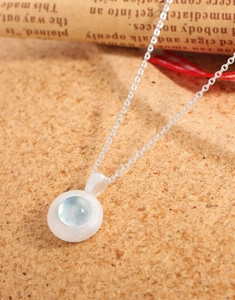 Close-up of S925 silver necklace featuring a matte round pendant with blue gemstone