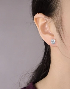 Close-up of a silver irregular lava texture flower earring worn by a model in profile