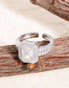 Macro view of emerald-cut zircon ring with twisted cable band on natural wood branch