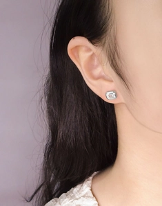 Close-up of minimalist S925 silver stud earring with emerald cut zircon on ear
