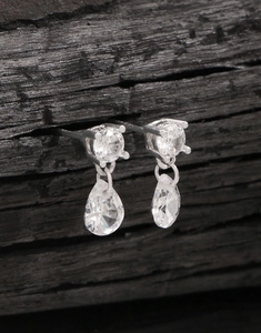 Macro shot of S925 silver pear-shaped cubic zirconia earrings on black wood
