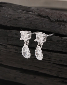 Macro shot of S925 sterling silver pear-shaped zircon earrings on a dark wood background