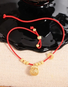 Macro shot of red braided bracelet with golden money bag charm and coins on mixed background