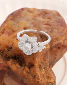 Dettaglio macro dell'anello in argento S925 con fiore in zircone e farfalla su roccia