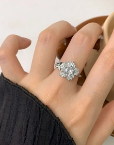 Dettaglio dell'anello a fiore in argento con zirconi e farfalla su sfondo lifestyle