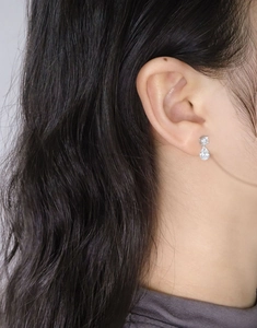 Close-up of minimalist S925 sterling silver pear-shaped zircon drop earrings on ear