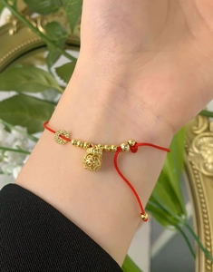 Close-up of S925 silver red string bracelet with gold money bag charm and woven detail