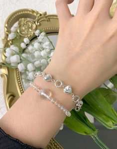 Détail de bracelet superposé en argent S925 et gourmette de perles de cristal clairs