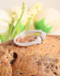 Macro shot of silver shell open ring with zirconia stone on a textured mineral stone