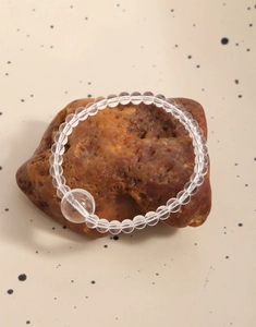 Détail d'un bracelet en perles de cristal naturel posé sur un support en pierre brute