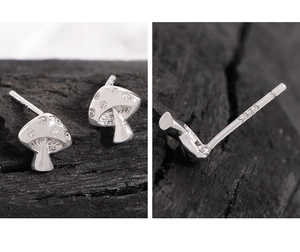 Macro detail of S925 sterling silver stamp and zircon mushroom stud earring on wood