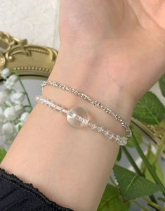 Gros plan d'une chaîne à billes argentée et d'un bracelet en cristal clair au poignet