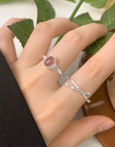 Detail view of natural strawberry quartz ring and cross layer silver band on hand