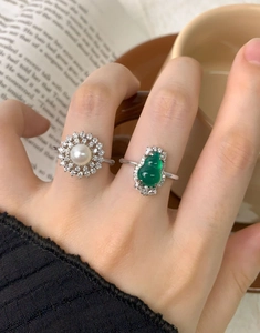 Macro shot of S925 silver rings with natural pearl and green gemstone in retro style