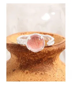 Macro detail of strawberry quartz ring with s925 silver textured band on pottery