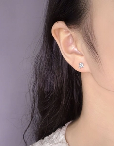Close-up of a minimalist silver mushroom stud earring with zircon on a model ear