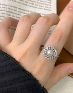 Detailed view of an S925 silver ring with a pearl center and zircon halo on a hand