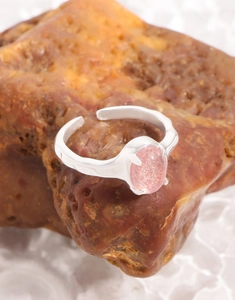 Macro shot of silver strawberry quartz ring on rustic rock with white textured background