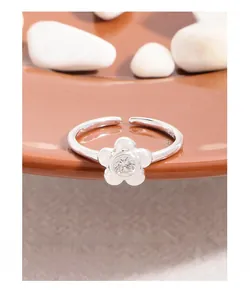 Detailed view of S925 sterling silver flower ring with zircon on a brown ceramic plate