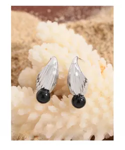 Macro view of S925 sterling silver wing earrings with black onyx bead on coral
