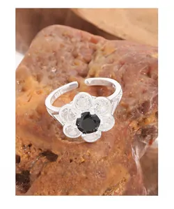 Macro shot of S925 silver flower ring with black stone center on red mineral rock