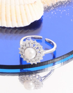 Detail of S925 silver pearl ring with sparkling zircon halo on a sea shell background
