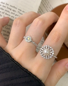 Detail of S925 silver rings with halo opal and pearl floral design on a vintage background