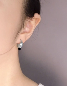 Close-up of S925 sterling silver earrings with wavy texture and black onyx bead pendant