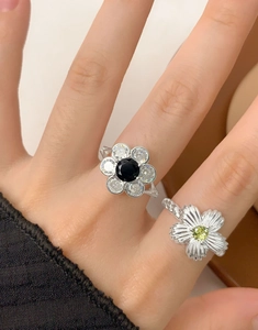 Detail of S925 silver rings with black and green zircon flower designs and textured bands