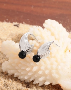 Detailed view of silver shell texture earrings with black onyx bead on coral display